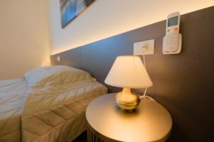 a bedroom with a bed and a table with a lamp at Camera Nairobi - La Casa di Carta Affittacamere in Udine