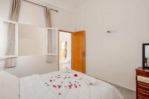 a bedroom with a white bed with red flowers on it at Retraite Panoramique sur l'Atlas in Ourika