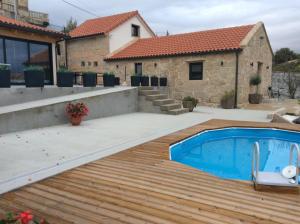 a swimming pool with a wooden deck and a house at Casa Chare in Moaña