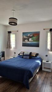 a bedroom with a blue bed and a painting on the wall at Alkimia del Río - Hogar, Arte, Piscina y Confort frente al Río in Potrero de los Funes