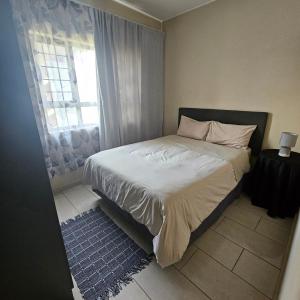 a small bedroom with a bed with a window at Modern 2 bedroom at Waterfall Ridge-Midrand in Midrand