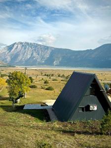 a barn in a field with a mountain in the background at Blidinje Lake House in Blidinje