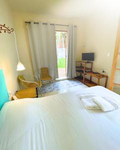 a bedroom with a bed and a desk and a window at Suíte no Jardim à Beira-Mar in Peruíbe