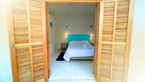 a small bedroom with a bed in a room with wooden doors at Suíte no Jardim in Peruíbe