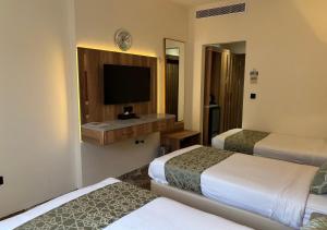 a hotel room with two beds and a flat screen tv at هندباء Hindibaa in Al ‘Azīzīyah