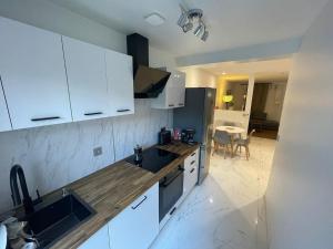 a kitchen with white cabinets and a sink and a table at Pavillion Peuple de l'Herbe in Carrières-sous-Poissy