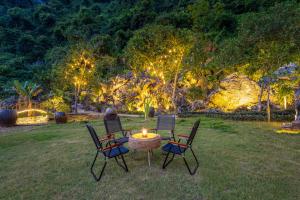 three chairs and a table with a candle in the grass at Cat Ba Serena Homestay And Swimming Pool in Cat Ba +138 photos