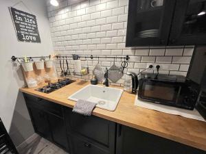 a kitchen counter with a sink and a microwave at Zlatá Víla by Cañas Apartments V srdci mesta, len pár krokov od hlavného námestia in Rimavská Sobota