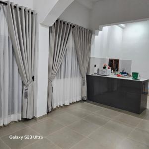 a kitchen with curtains and a counter with a microwave at Moon Guest House in Trincomalee