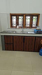 a kitchen with a sink and two windows at Moon Guest House in Trincomalee