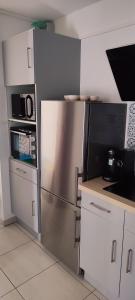 a kitchen with white cabinets and a stainless steel refrigerator at Le Petit Clazayéen in Bressuire +3 photos