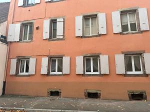 ein orangefarbenes Gebäude mit weißen Fensterläden in der Unterkunft Le petit nid de cigogne in Colmar