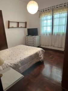 a bedroom with a bed and a dresser and a television at Alquilo Casa Miramar in Miramar