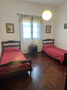 a bedroom with two beds and a table and a window at Alquilo Casa Miramar in Miramar