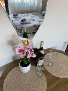 ein Tisch mit zwei Weingläsern und einer Vase mit Blumen in der Unterkunft M&A apartman in Jagodina