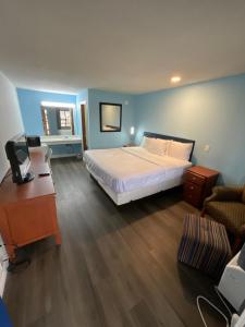 a bedroom with a white bed and a blue wall at Oak Tree Inn in Irvine