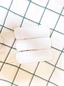 four white towels stacked on a tiled floor at Poppy ikebukuro in Wada