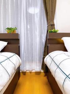 two twin beds in a room with a window at Poppy ikebukuro in Wada