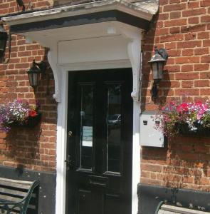 una puerta negra en un edificio de ladrillo con flores en The Horse and Groom Guest House, en Swaffham