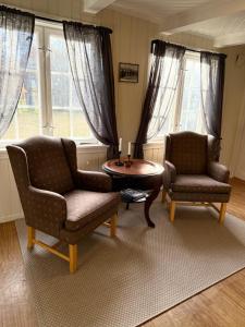 a living room with two chairs and a table at Private pearl in downtown Røros in Røros
