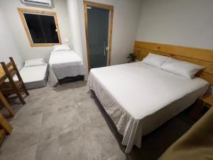 a bedroom with a large white bed and a window at Suíte no Rancho Minas in Porto Seguro
