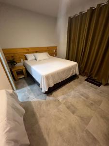 a bedroom with a white bed and a curtain at Suíte no Rancho Minas in Porto Seguro +1 photo