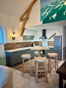 eine Küche mit einem Tisch und einigen Hockern in der Unterkunft Gîte Les Aubracs - Puy de Dôme - Massif du Sancy in Saurier