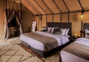 1 dormitorio con 2 camas en una tienda de campaña en Hayati Desert Luxury Camp, en Merzouga