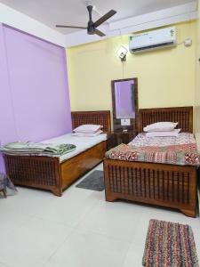 two beds in a room with a ceiling fan at Meera Hotel And Lodging in Badarpur