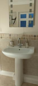 Un lavabo blanco en un baño con espejo. en 9 Church View, en Clapham