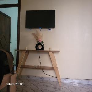 einen Flachbild-TV an einer Wand mit einem Holzregal in der Unterkunft Chambre dans maison rénovée in Commercy