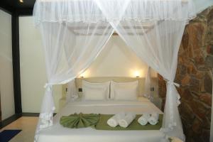 a bedroom with a bed with white curtains and towels at Mindara Villa in Galle