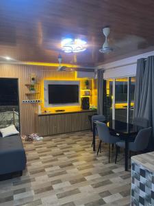 a living room with a table and a yellow wall at Heyleez Guest House in Himmafushi