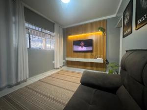 un salon avec un canapé et une télévision au mur dans l'établissement Yes João & Maria Casa inteira com garagem 7km aeroporto GRU, à Guarulhos