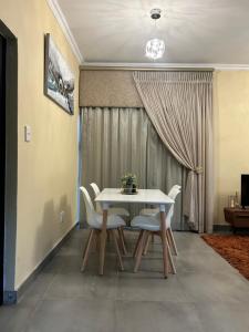 a dining room with a white table and chairs at Katlego in Bloemfontein