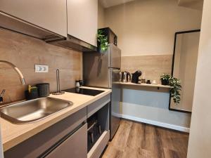 a kitchen with a sink and a stainless steel refrigerator at Piata Romana Suites & apartments - Pumo Properties in Bucharest