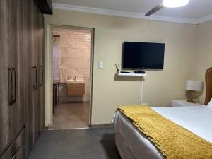 a bedroom with a bed and a television on the wall at Katlego in Bloemfontein +10 photos