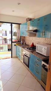 a kitchen with blue cabinets and a white tile floor at Appartement Moderne avec Piscine in Bouznika