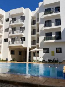 a hotel with a swimming pool in front of a building at Appartement Moderne avec Piscine in Bouznika