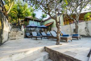 Un grupo de sillas y sombrillas en un patio. en Ware Ware Surf Bungalow Lembongan, en Nusa Lembongan