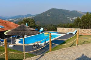a swimming pool with an umbrella next to a house at Refúgio in Castelo de Paiva