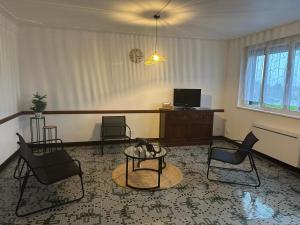 een woonkamer met stoelen, een tafel en een tv bij Les mirabelliers 