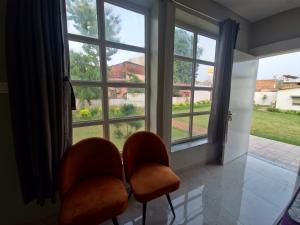 Niwaas Stay في فاراناسي: كرسيان برتقاليان يجلسان أمام نافذة كبيرة