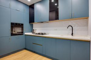 a kitchen with blue cabinets and a sink at Luxor Collection Apartments in Tbilisi City