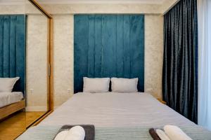 a bedroom with a large bed and a blue wall at Luxor Collection Apartments in Tbilisi City