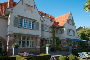 een groot wit huis met blauwe ramen bij Romantik B&B Zonnehuis in De Haan