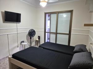 a bedroom with a bed and a fan and a window at Varandas do Atlântico in Guarujá
