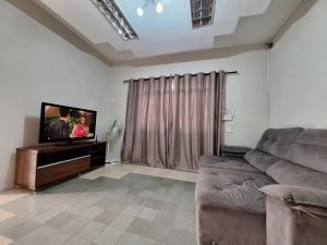 a living room with a couch and a flat screen tv at Casa 4 quartos no centro da cidade - 3 vagas de garagem in Campo Grande +52 photos