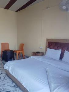 a large white bed in a room with a chair at Prithvi hotel and restaurant in Mussoorie +9 photos