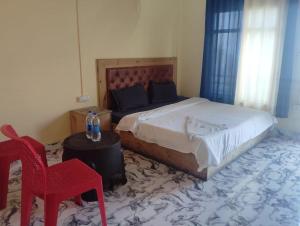 a bedroom with a bed and a red chair at Prithvi hotel and restaurant in Mussoorie